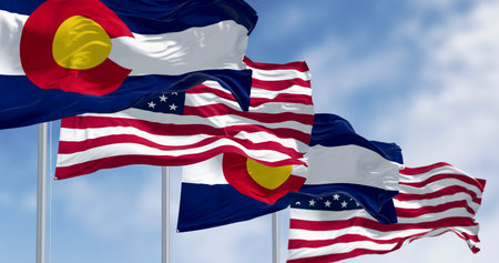 The Stars and Stripes and the Colorado state flag flying together on flagpoles. Concept of the relationship between state and the federal government, and American patriotism. 3D illustration.の写真素材