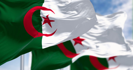 Algeria national flags waving in the wind on a clear day. Two vertical bars, green and white, with a red star and crescent in the center. 3d illustration render. Fluttering fabric backgroundの写真素材