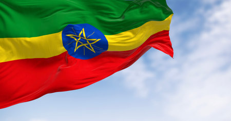 Ethiopia national flag waving on a clear day. Horizontal bands of green, yellow, and red with the...