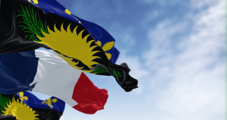 Guadeloupe flag waving with french national flag on a clear day. Overseas department and region of...