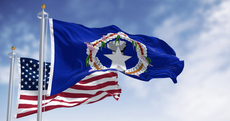 Flags of Northern Mariana Islands waving in the wind with the US flag on a clear day. The Northern Mariana Islands are an unincorporated territory and commonwealth of the United Statesの写真素材