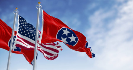 Tennessee state flag waving with the american flag on a clear day. Three white stars inside a blue...