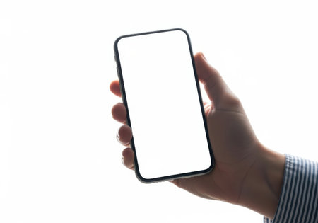 A person's hand holds a modern smartphone with a blank white screen, ready for content or interaction. Isolated on white.の素材