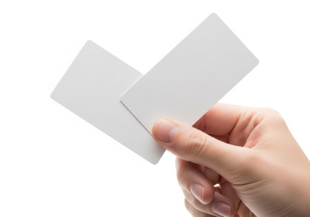 A close-up shot of a hand holding two blank white cards, isolated on a white background. The cards are angled and slightly overlapping.の素材