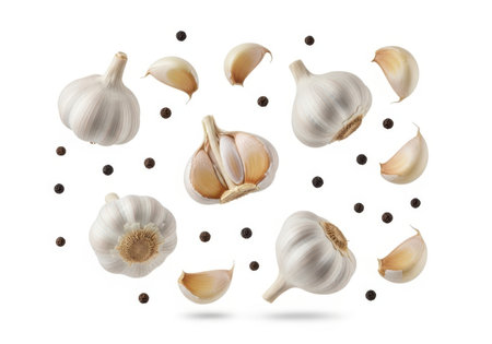 A dynamic arrangement of whole garlic bulbs, peeled cloves, and black peppercorns floating against a clean white background.の素材