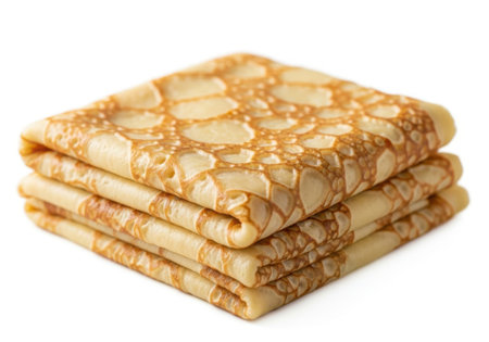 A neat stack of three thin, golden brown pancakes or crepes, folded and presented on a clean white surface.の素材