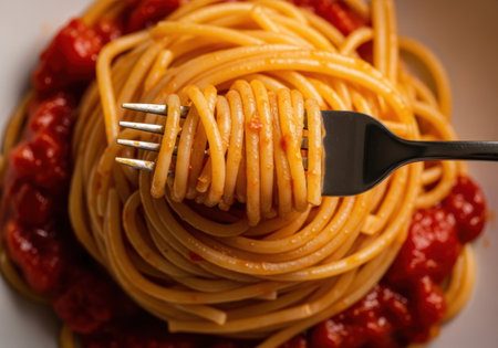 Spaghetti with tomato sauce on a white plate close-up.の素材