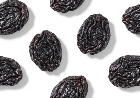 A pattern of dark, wrinkled raisins is arranged on a clean white surface, creating a visually appealing food composition.の素材