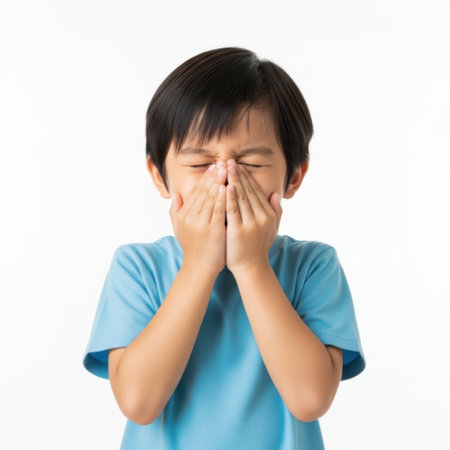 A young boy with his eyes squeezed shut covers his mouth and nose with both hands, conveying a strong sense of disgust or revulsion.の素材