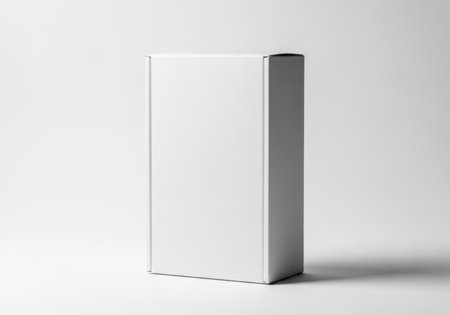 A plain white book stands vertically on a white surface, casting a subtle shadow. The cover is completely blank.の素材