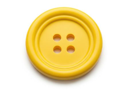 A close-up studio shot of a single, bright yellow, four-hole sewing button with a textured rim, isolated on a clean white background.の素材