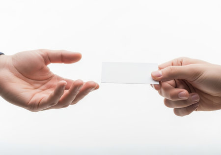 Two hands exchange a blank white business card against a clean white background, symbolizing networking and introduction.の素材
