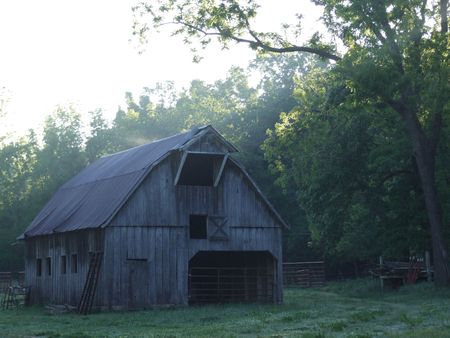 Barn; old barn on farm/ranch at sunrise with rays of light shinningの写真素材