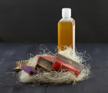 SPA treatment set: natural soap, shower gel, wisp and comb on dark wooden backgroundの写真素材