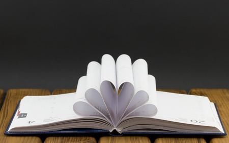 Open notebook with white sheets of paper folded fan on wooden backgroundの写真素材
