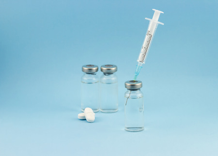 Healthcare and medical concept. Glass ampoules with syringe and tablets on blue backgroundの写真素材
