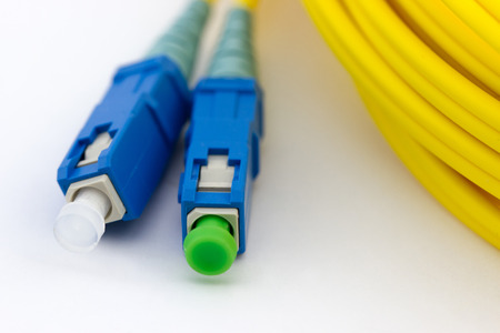 Hank of yellow optic cable with blue patch cord connectors isolated on white background