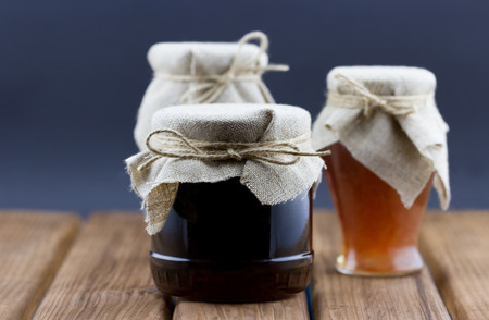 Glass jars of jam and honey on wooden backgroundの写真素材