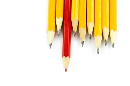 One red pencil standing out from the row of yellow pencils isolated on white backgroundの写真素材