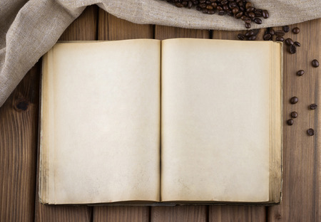 Top view of blank old book with sackcloth and cofee beans on wooden background