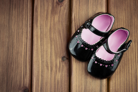 Top view of little girl shoes with hearts on wooden backgroundの写真素材