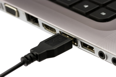 USB cable plugged in to laptop computer isolated on white background