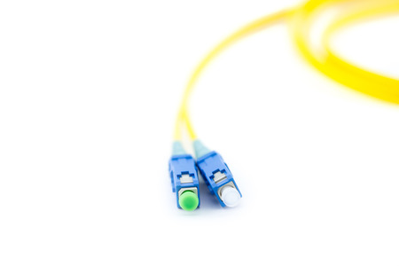 Close up yellow optic cable with blue patch cord connectors isolated on white backgroundの写真素材