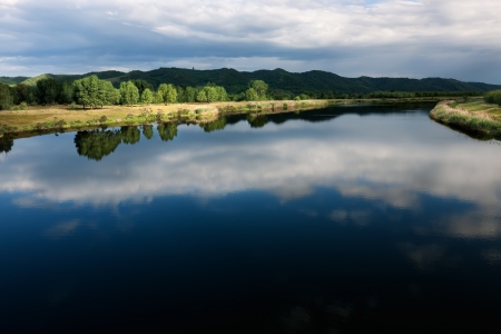 The river channel with a quiet current and clouds reflected in it の写真素材