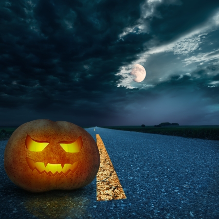 Jack O Lantern halloween pumpkin at night on the empty asphalt roadの写真素材
