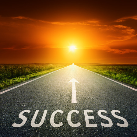 Empty asphalt road towards the sun and sign symbolizing success の写真素材