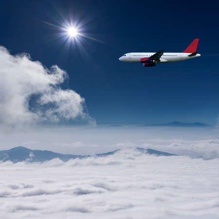 White airplane flying at high altitude above the clouds against the the sunの写真素材