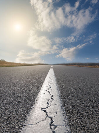 Driving on an empty road at sunny day. Focus on the beginning of the asphalt roadの写真素材