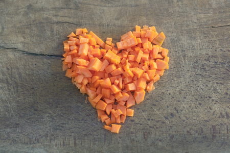 Chopped carrots arranged in the shape of heart on vintage wooden board. concept for loveの写真素材