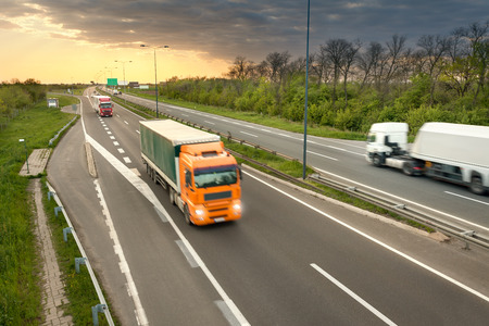 Three trucks in motion blur on the freeway towards the setting sun. Rush hour on the motorway near Belgrade - Serbia.の写真素材