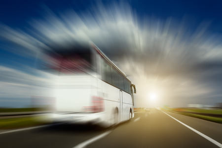 White bus in blurred motion at full speed performs overtaking on the highway. Photographed from the car when driving.