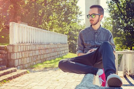 One young hipster sitting lone otdoors.の写真素材
