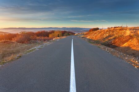 Driving on an empty asphalt road through the idyllic hills at autumn season in mountain area. Mountain Golija, Serbia.の写真素材