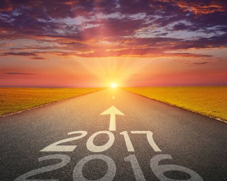 Driving on an empty road towards the setting sun to upcoming 2017 and leaving behind old 2016.の写真素材