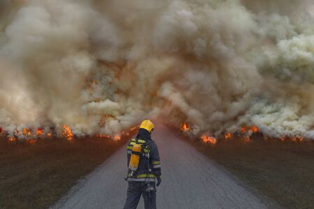Firefighters on the ground trying to slow the spread of a large fire.の写真素材