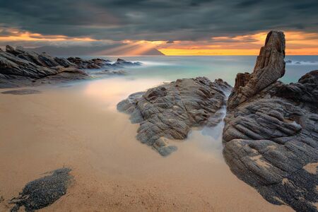 Greek coast of Aegean sea at dramatic morning with holy mountain Athos in clouds. Chalkidiki, Greece. Long exposure shot with beautiful sunbeams.の写真素材