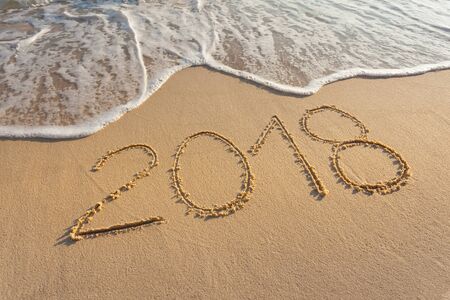 Number 2018 handwritten on sandy coastline. Concept of upcoming new year and passing of time.