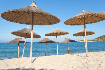 Many straw sun umbrellas on the sandy beach as concept for idyllic summer holiday.の写真素材