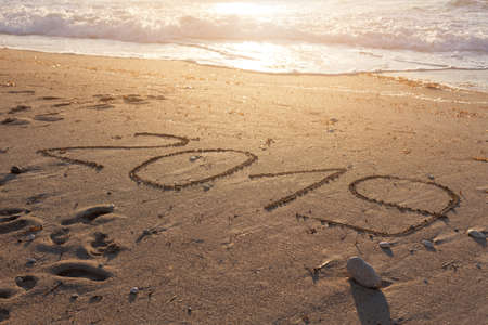 2019 digit handwritten on idyllic sandy beach with waves in background. Concept of upcoming new year and passing of time.の写真素材