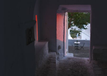 Dark passage with table and chairs in background at Pyrgos village. Santorini island, Greece.の写真素材