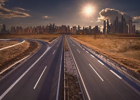 Empty motorway towards the sun and cityscape at beautiful sunset.の写真素材