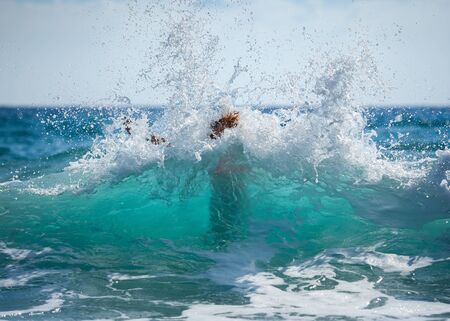 Girl have fun during hot summer day playing with waves in beautiful turquoise sea water on vacation.の写真素材