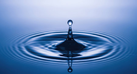 Water drop on water surface with ripples and waves. Blue backgroundの写真素材