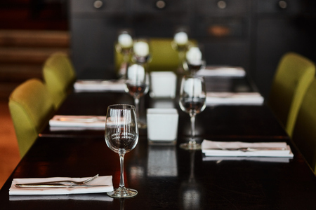 Dining table served with glasses, forks and knifes.