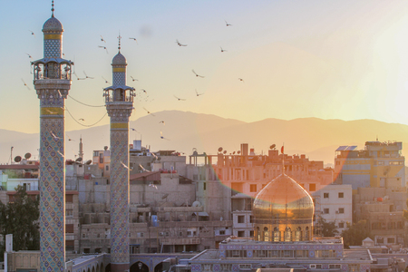 External shot for Sayeda Zeinab shrine in Damascus capital of Syria which showing the shrine with one golden dome and two minarets and some Residential buildings.