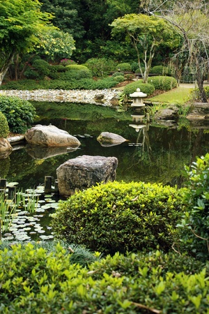 neat Japanese style garden with calm pond and typical lantern at a pondの写真素材